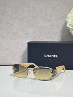 Gold-framed sunglasses with yellow-tinted lenses and side logo detail, metal temples