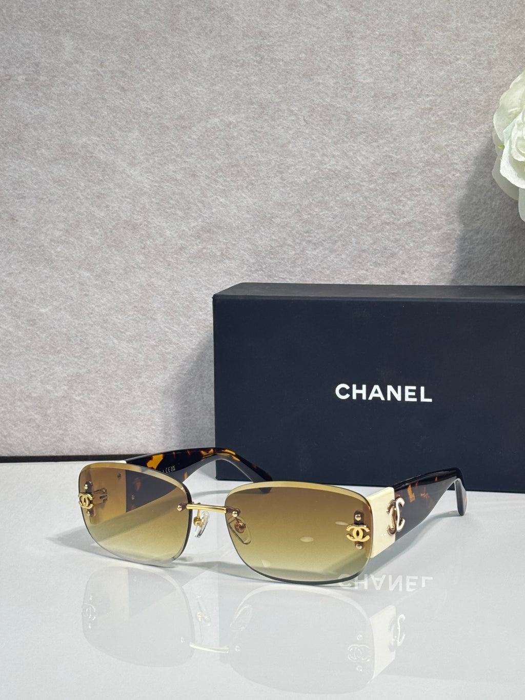 Gold-framed sunglasses with tinted amber lenses and side logo detail, metal temples
