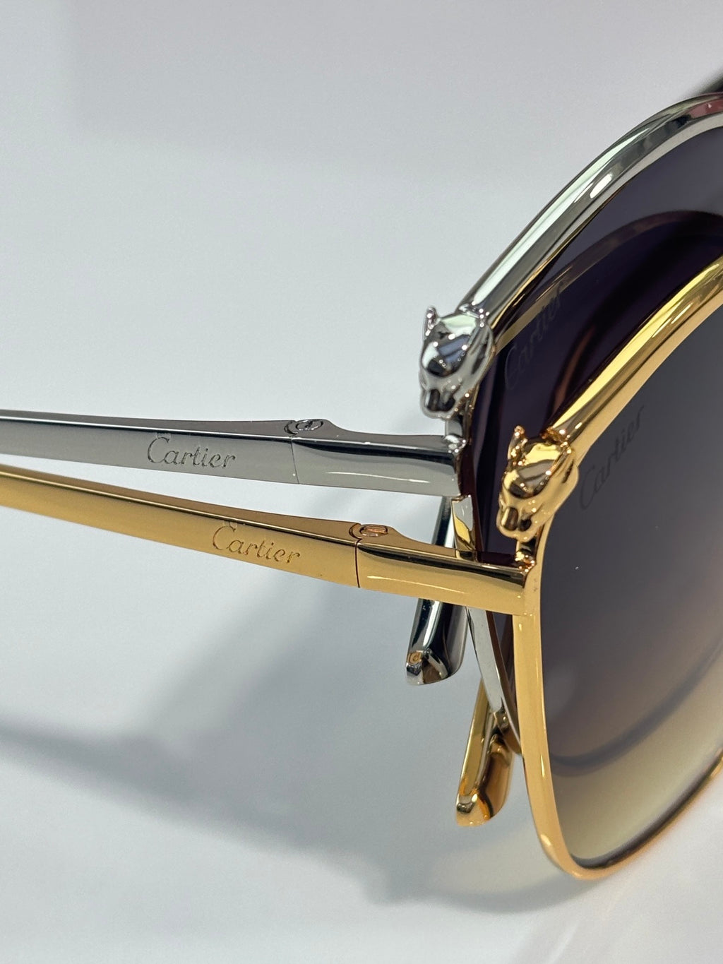 Cartier sunglasses close-up: chrome-and-gold temple with hinge detail