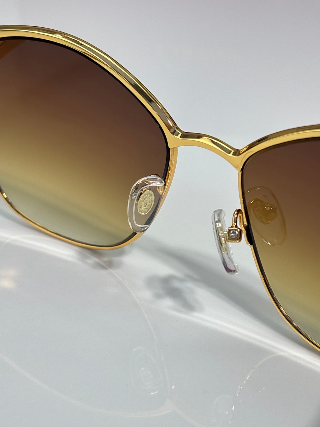 Cartier sunglasses close-up: gold round lens frame with metal logo detail