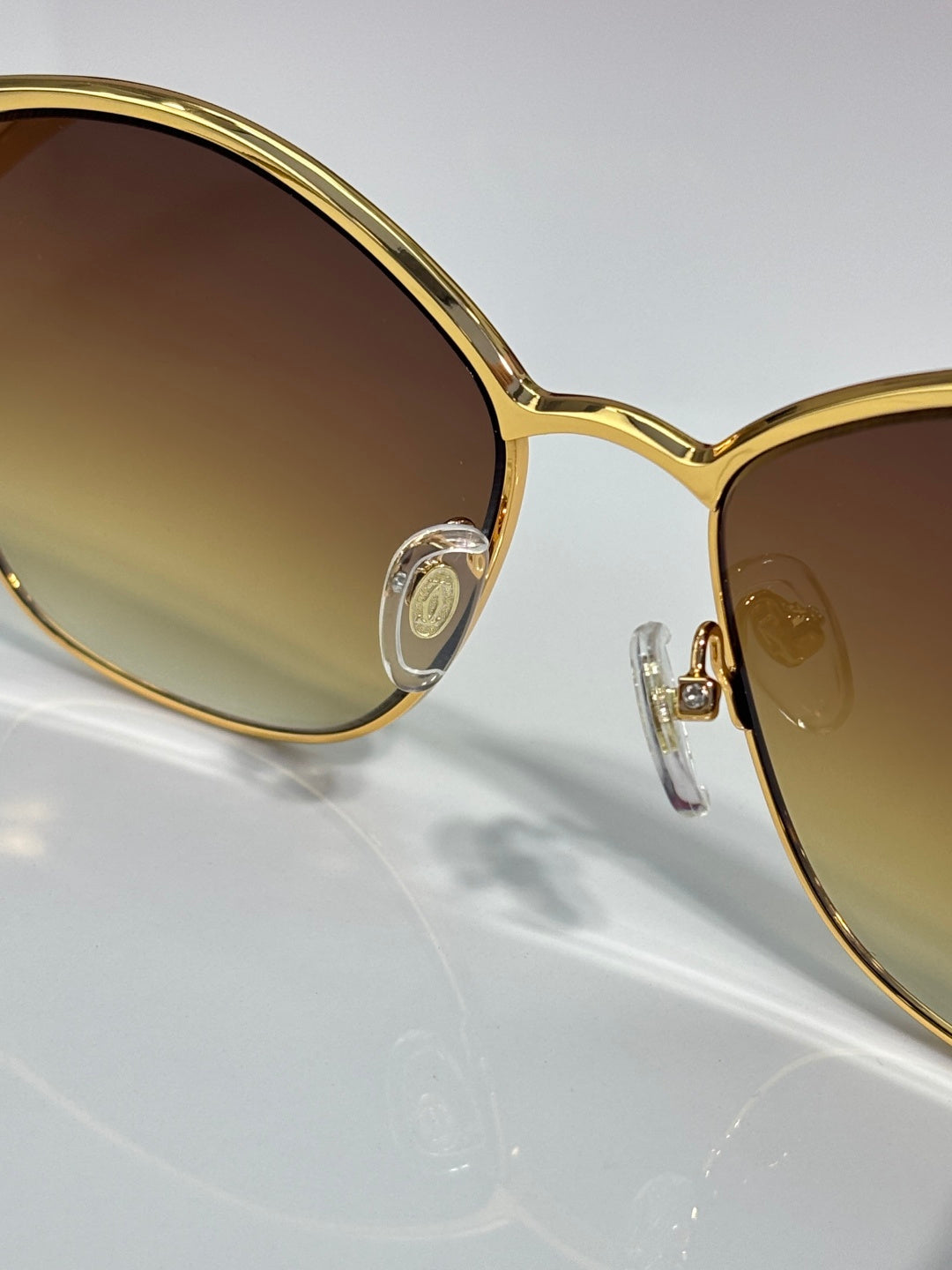 Cartier sunglasses close-up: gold round lens frame with metal logo detail