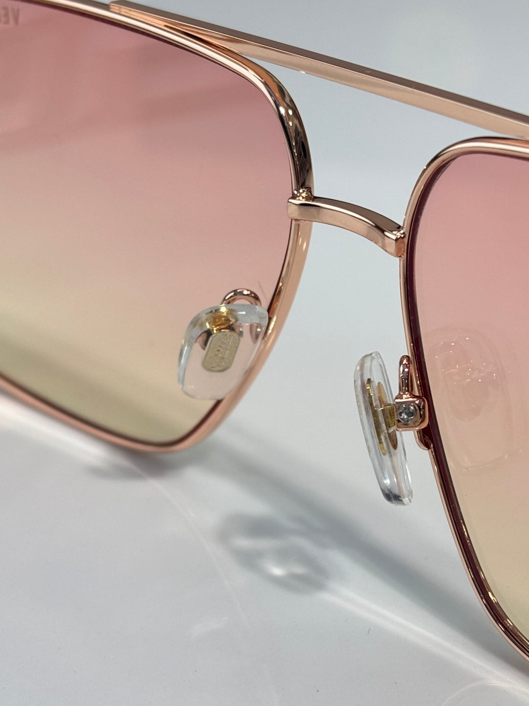 Versace sunglasses close-up of rose-gold frame and clear lens edge