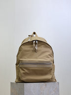YSL nylon backpack in tan with top handle, front zip pocket, and metal zipper pulls