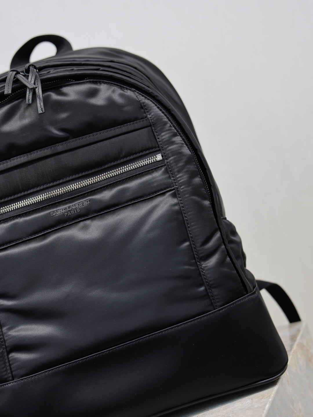 YSL black backpack close-up of front zipper pocket and stitched panel seams
