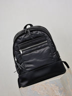 YSL black backpack with glossy front panel, two zip pockets, and tie pulls