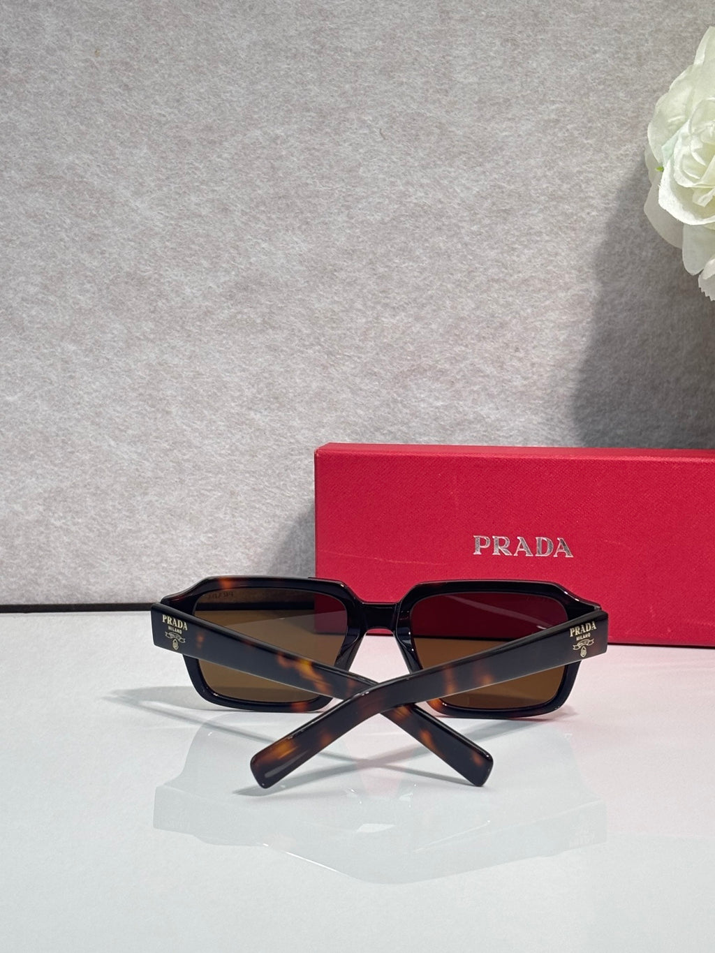 Tortoiseshell square sunglasses with dark lenses and crossed temples