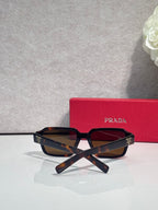 Tortoiseshell square sunglasses with dark lenses and crossed temples