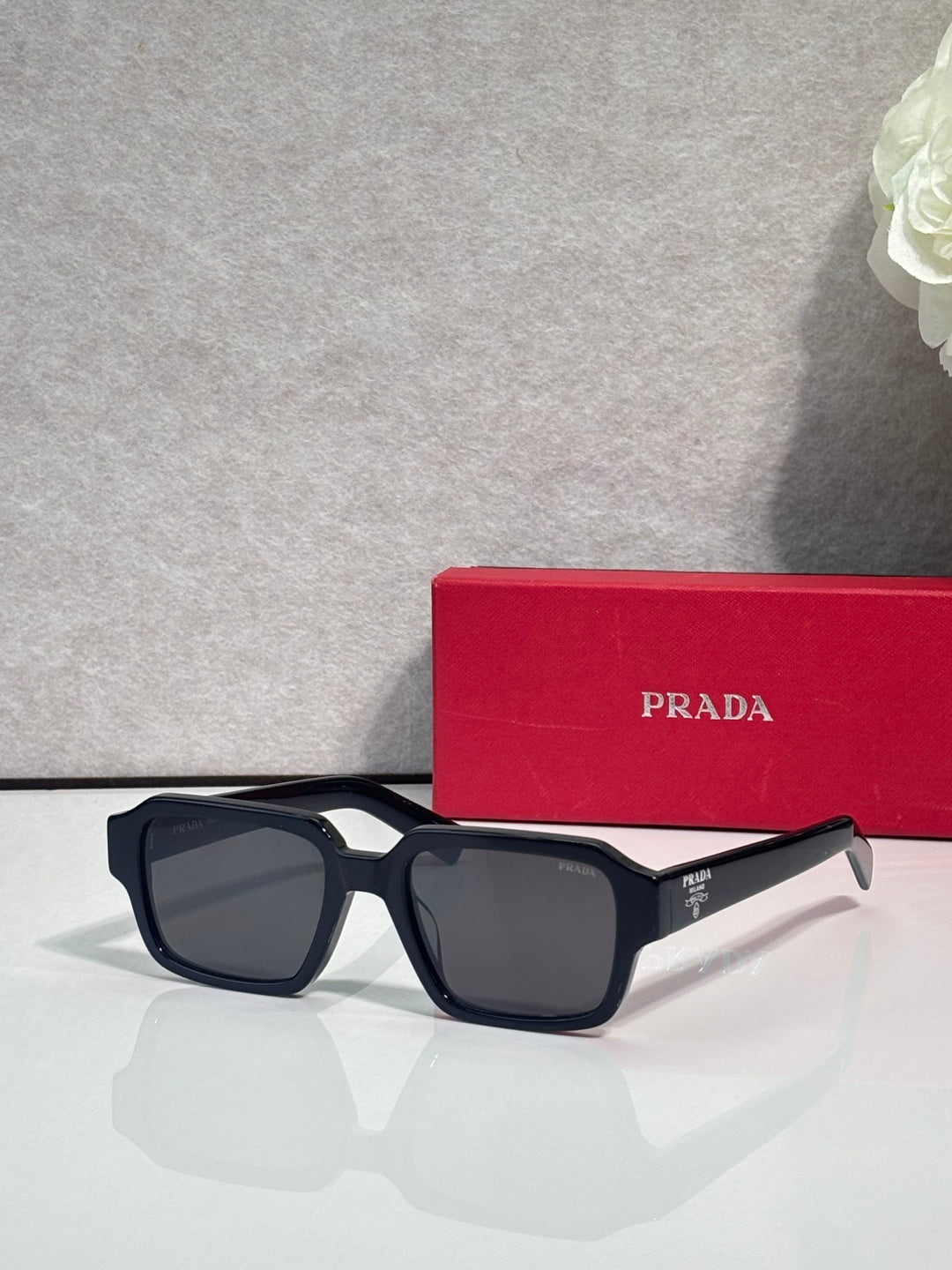 Black square sunglasses with dark lenses and silver logo detail