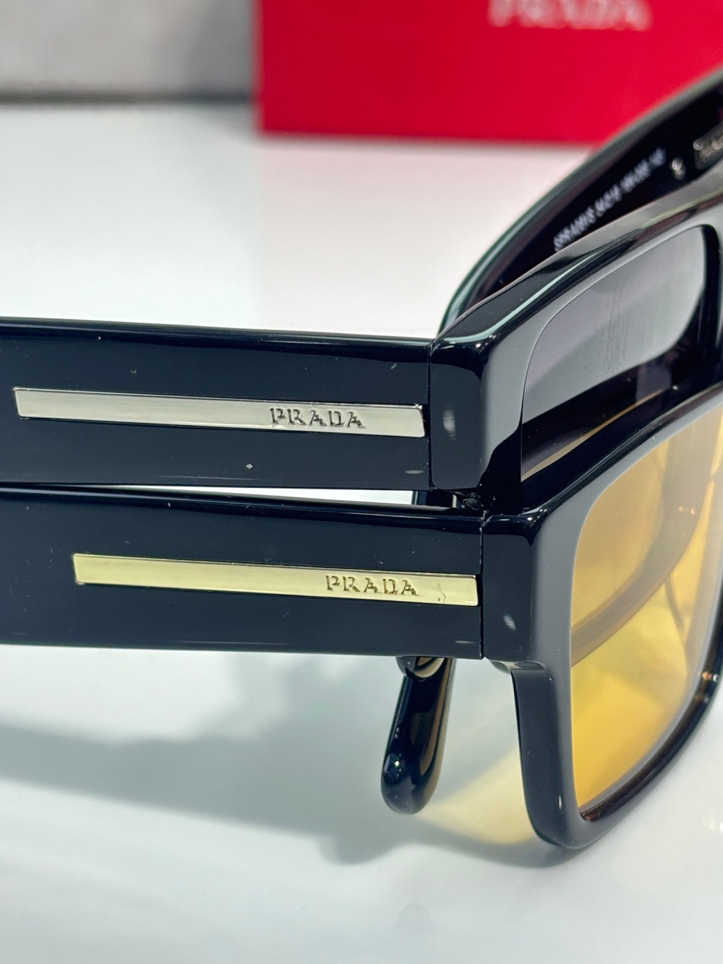 Prada sunglasses close-up of dark temples with yellow-tinted lenses