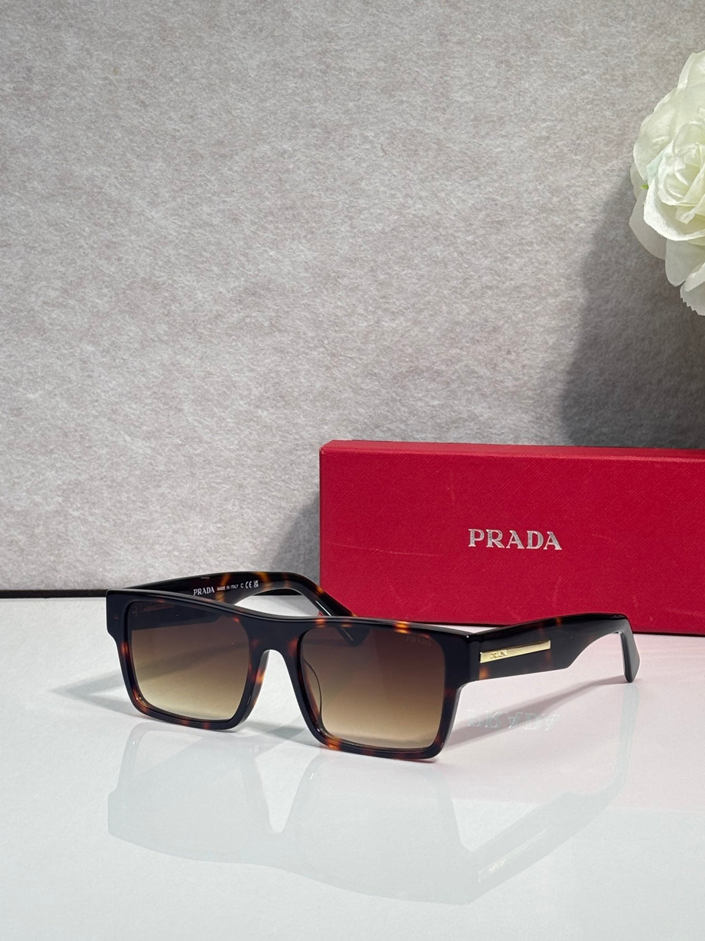Prada square sunglasses with dark frames and gradient brown lenses