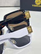 Versace closeup sunglasses with gold emblem hinges, dark blue frame and brown lenses