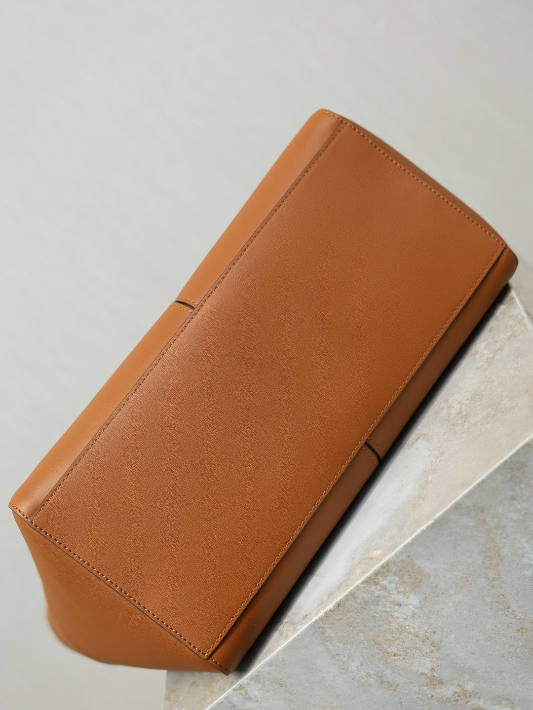 Tan-brown leather tote bag side profile with clean edge stitching