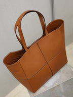 Brown leather tote bag with two handles and open top view of interior