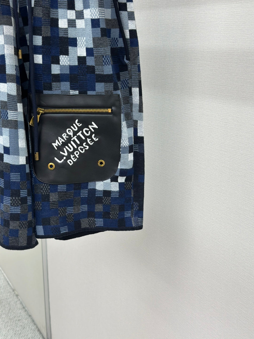 Blue pixel-check shorts with black side pouch, gold zipper, white logo