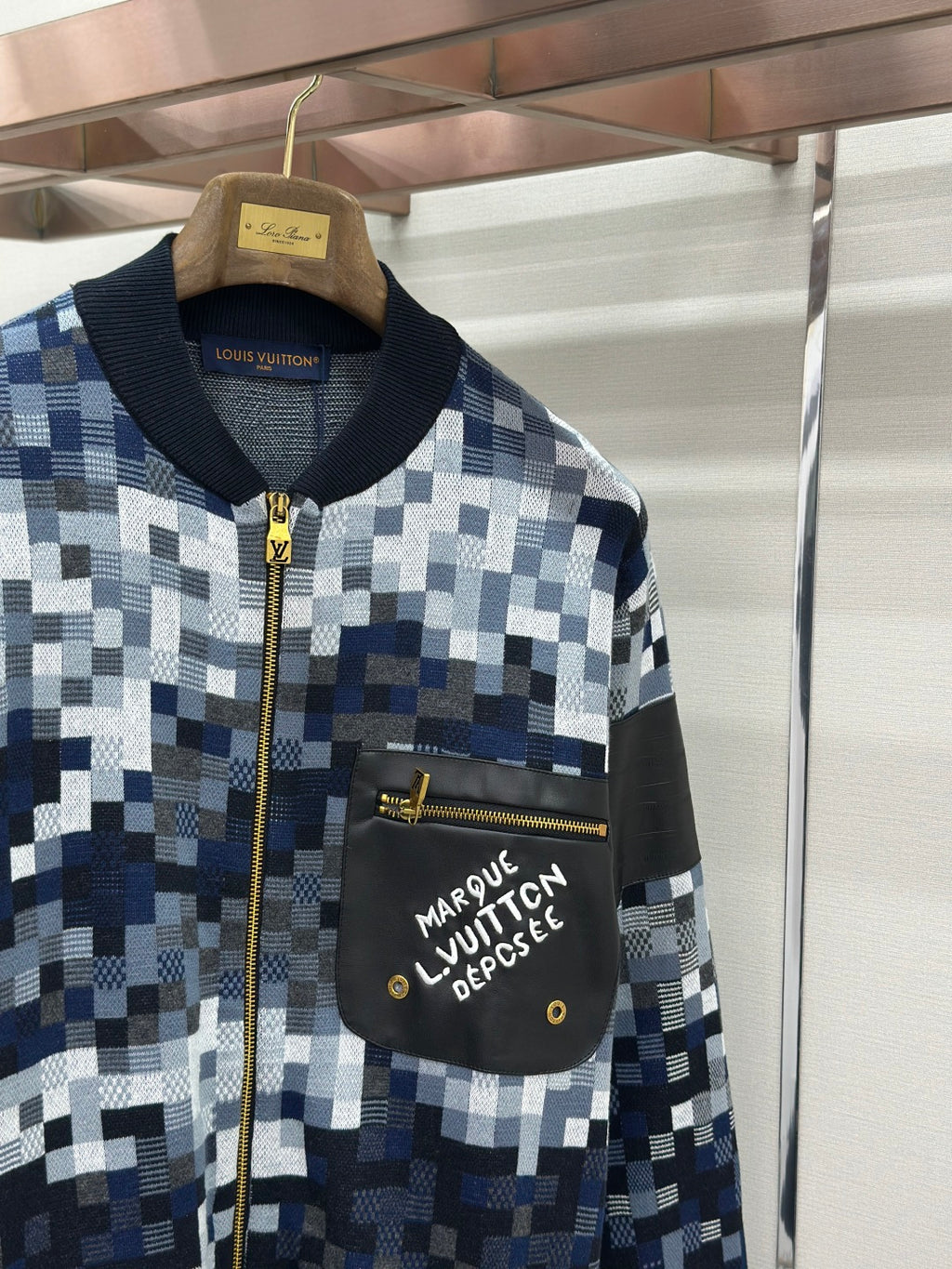 Zip-up jacket upper front, black chest pocket with Louis Vuitton text, gold zipper