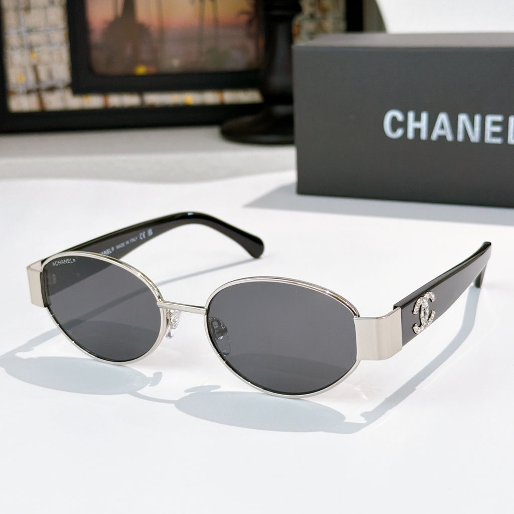 Silver and black round sunglasses with dark lenses; Chanel logo on side temples.