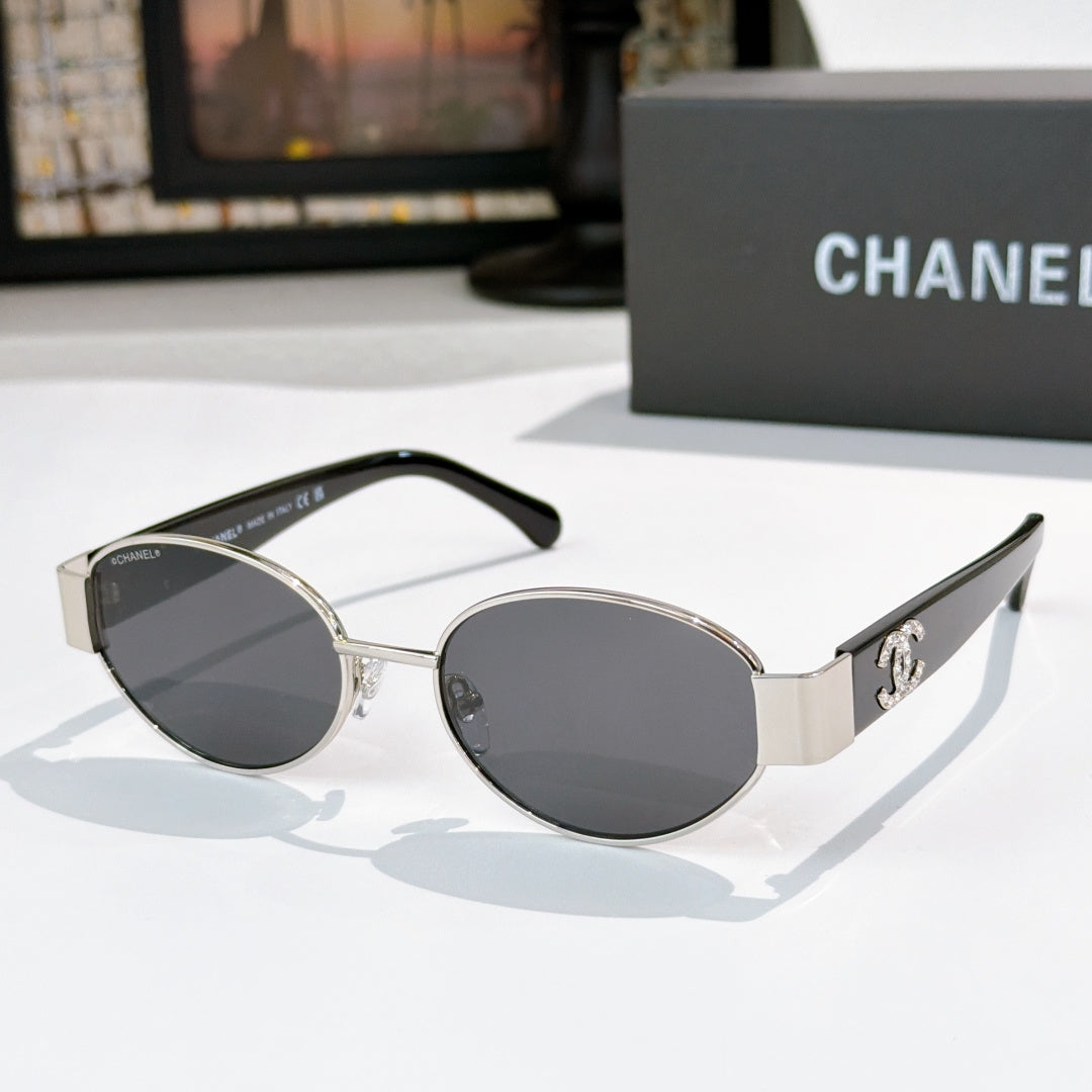 Silver and black round sunglasses with dark lenses; Chanel logo on side temples.