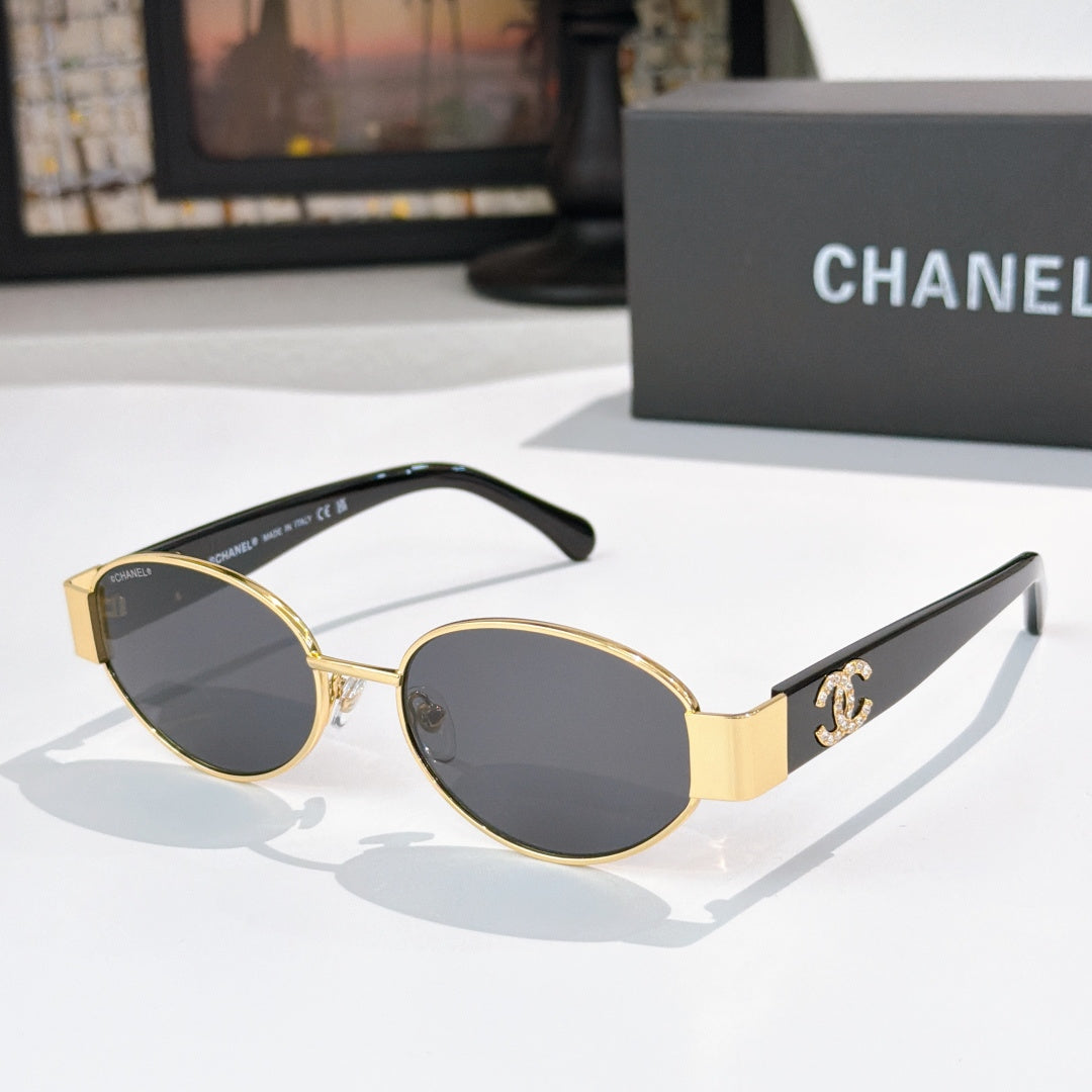 Gold-rim round sunglasses with dark lenses and black temples; Chanel logo on arms.