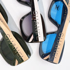 Chanel sunglasses close-up, showing black frames with beige-tan arms and blue lenses