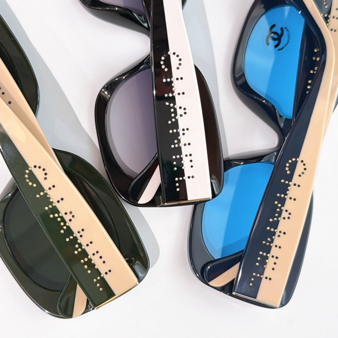 Chanel sunglasses close-up, showing black frames with beige-tan arms and blue lenses