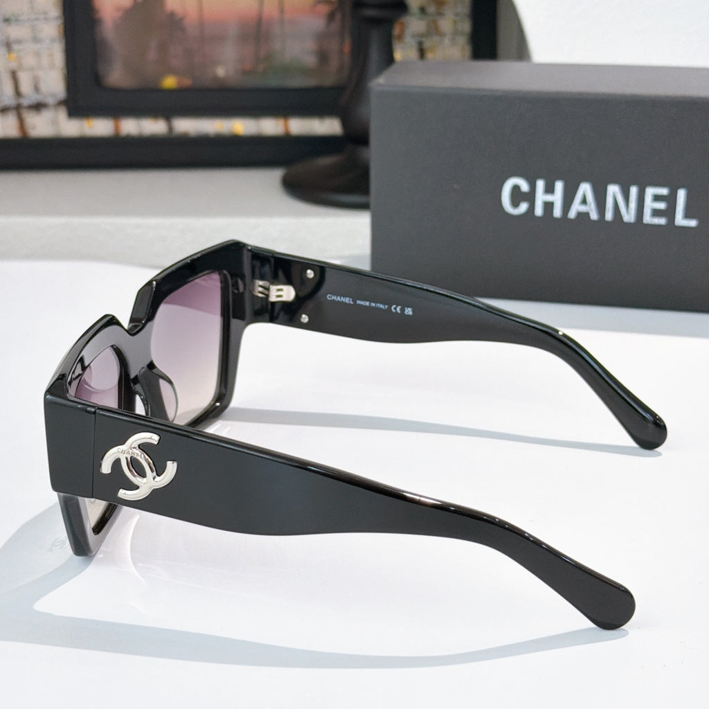 Oversized black sunglasses with purple tinted lenses and silver side logo