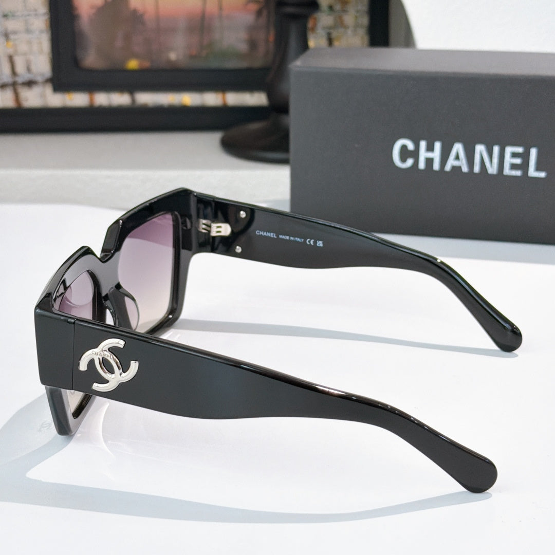 Oversized black sunglasses with purple tinted lenses and silver side logo
