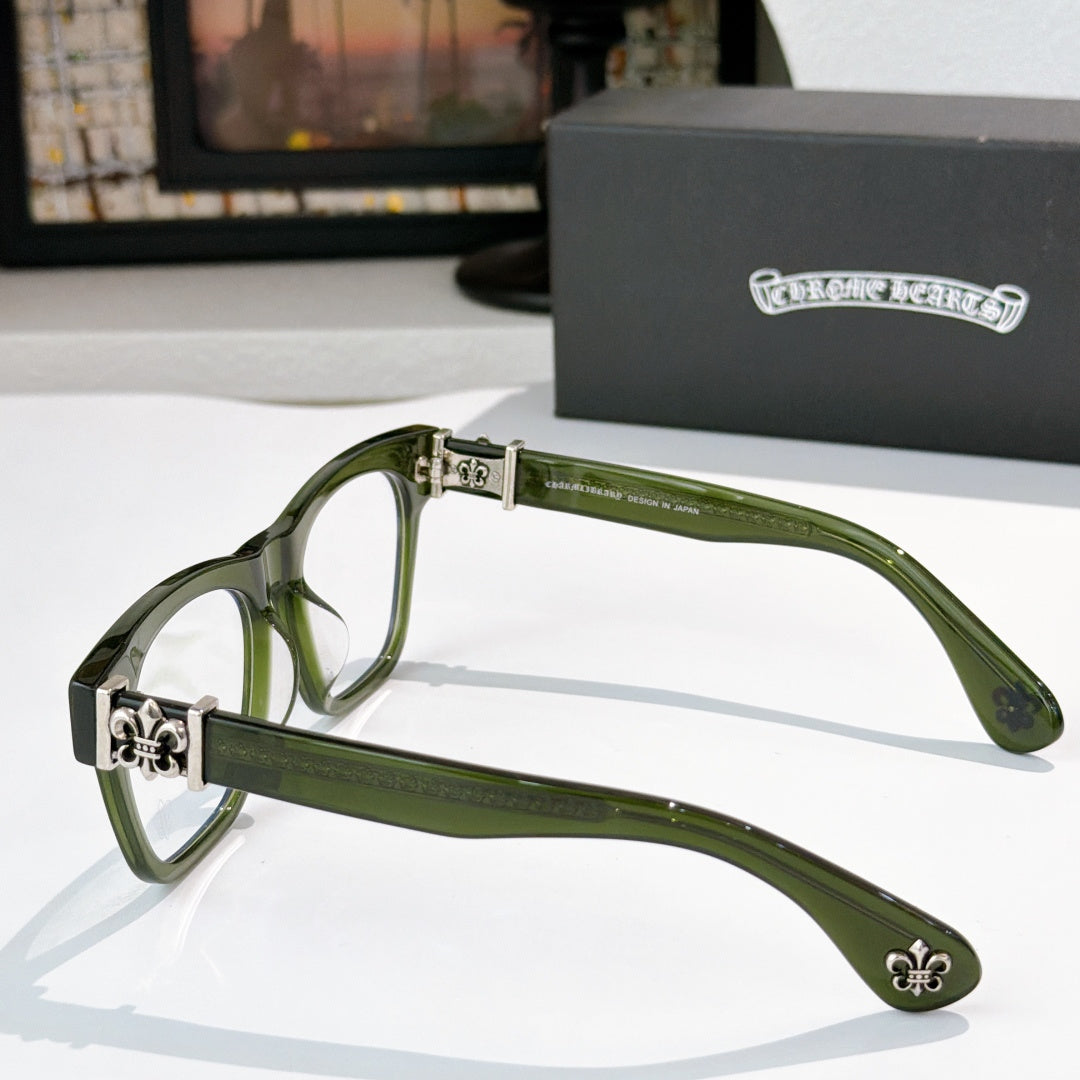 Green eyeglasses side view with ornate hinge and fleur-de-lis temple emblem.
