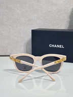 Chanel sunglasses with white frames and dark tinted lenses, gold CHANEL lettering on temples.