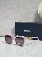 Chanel sunglasses with light pink frames and tinted lenses, gold logo accents.