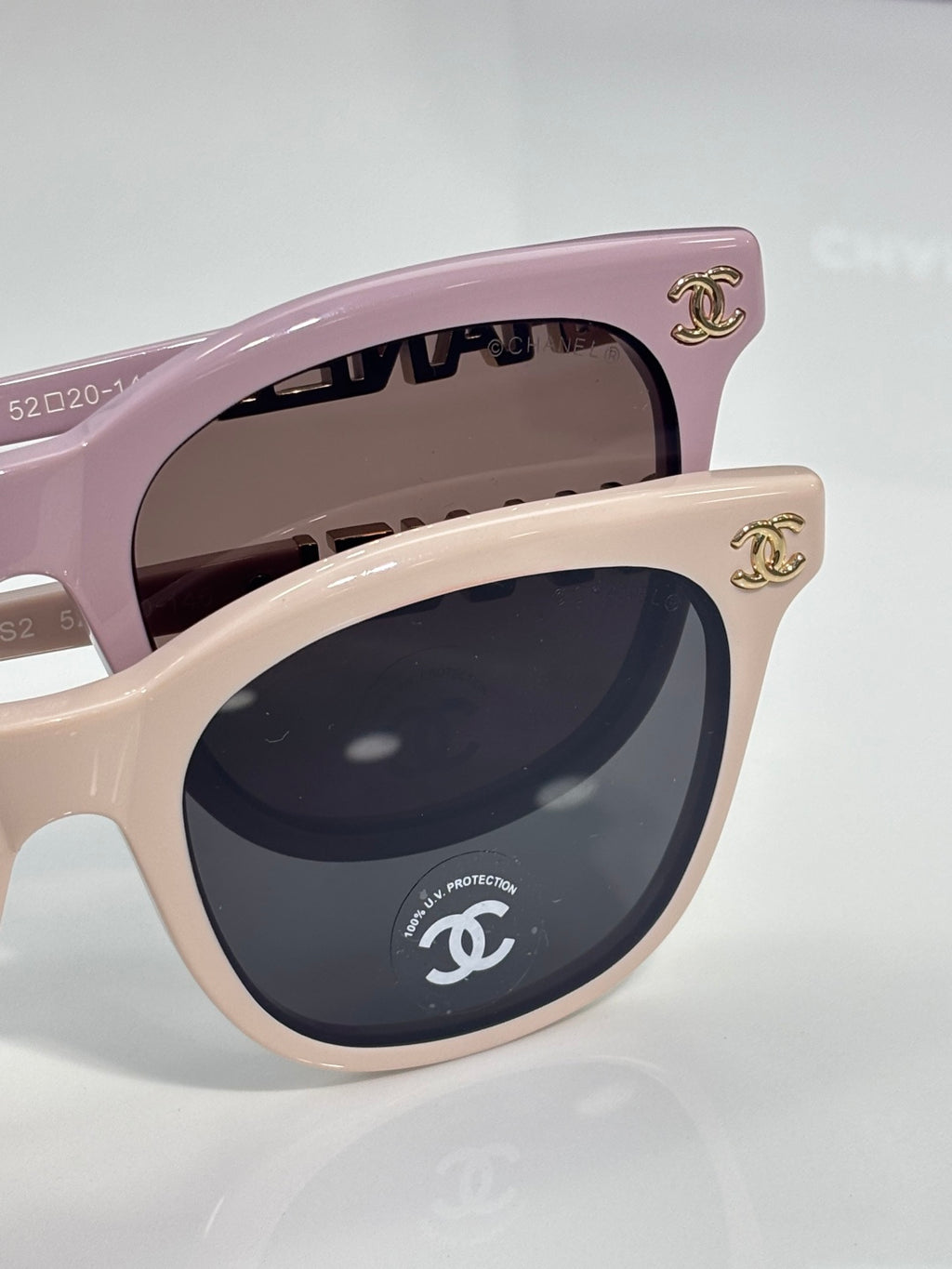 Chanel sunglasses close-up: light pink cat-eye frames with CHANEL emblem on the side.