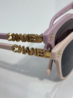 Chanel sunglasses close-up: pink frames with gold CHANEL lettering on the temples.