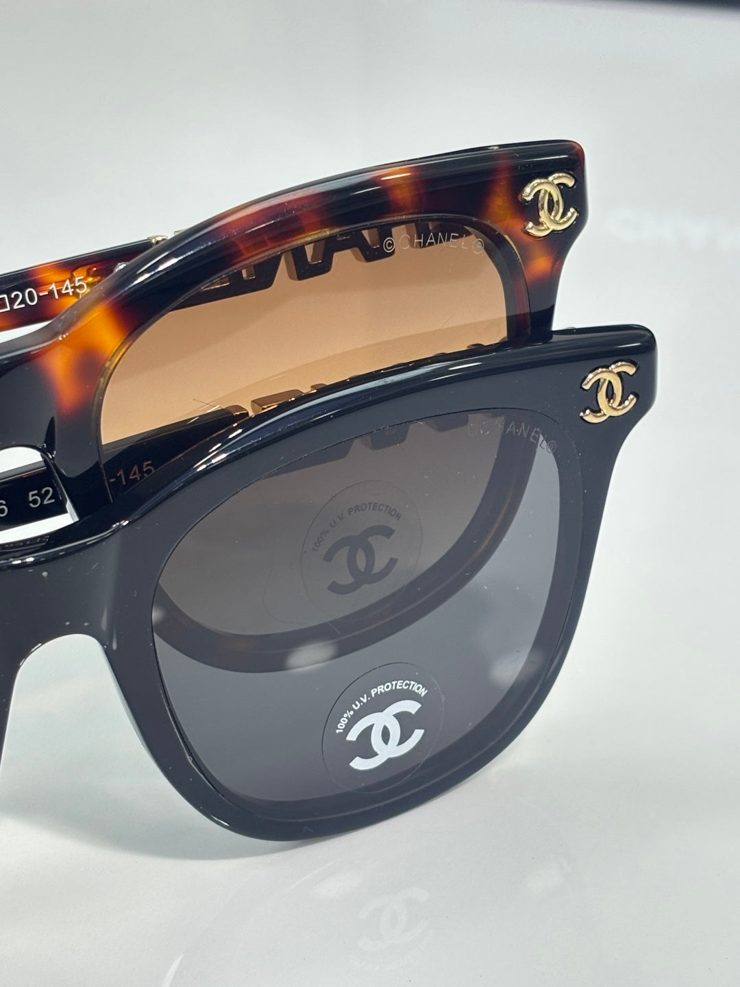 Chanel sunglasses close-up: dark tortoiseshell frames with CHANEL emblem on the temple.