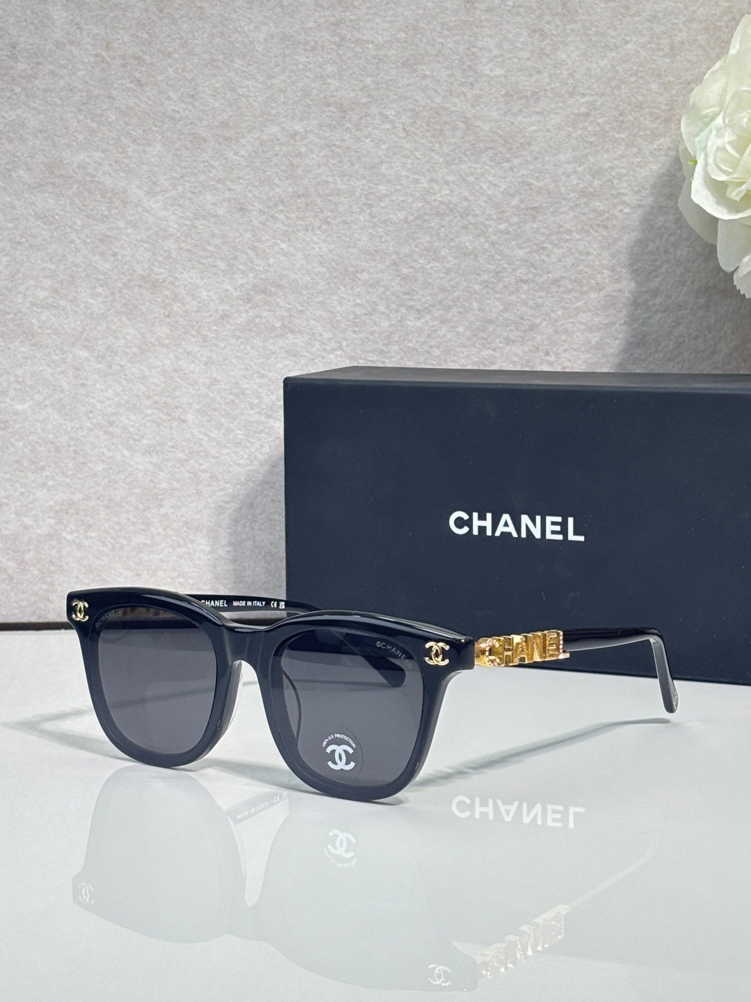 Chanel sunglasses with dark navy frames and tinted lenses, gold logo accents.