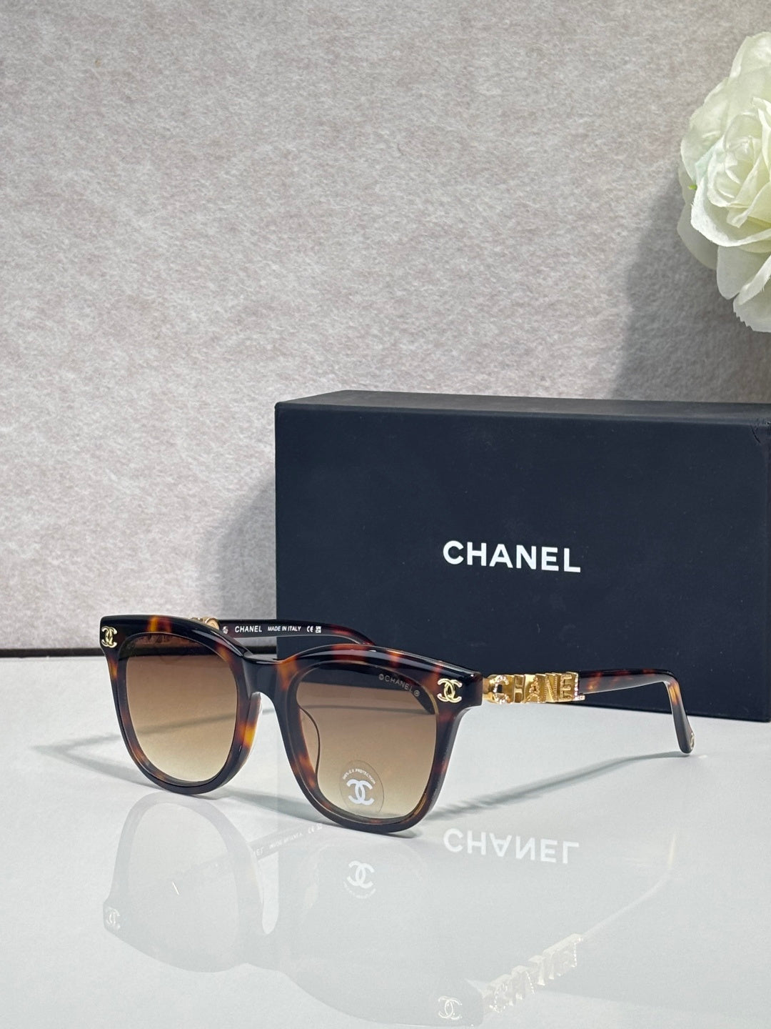 Chanel sunglasses with tortoiseshell frames and tinted lenses, gold logo accents.