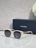 Chanel sunglasses with cream frames and dark tinted lenses, gold logo accents.