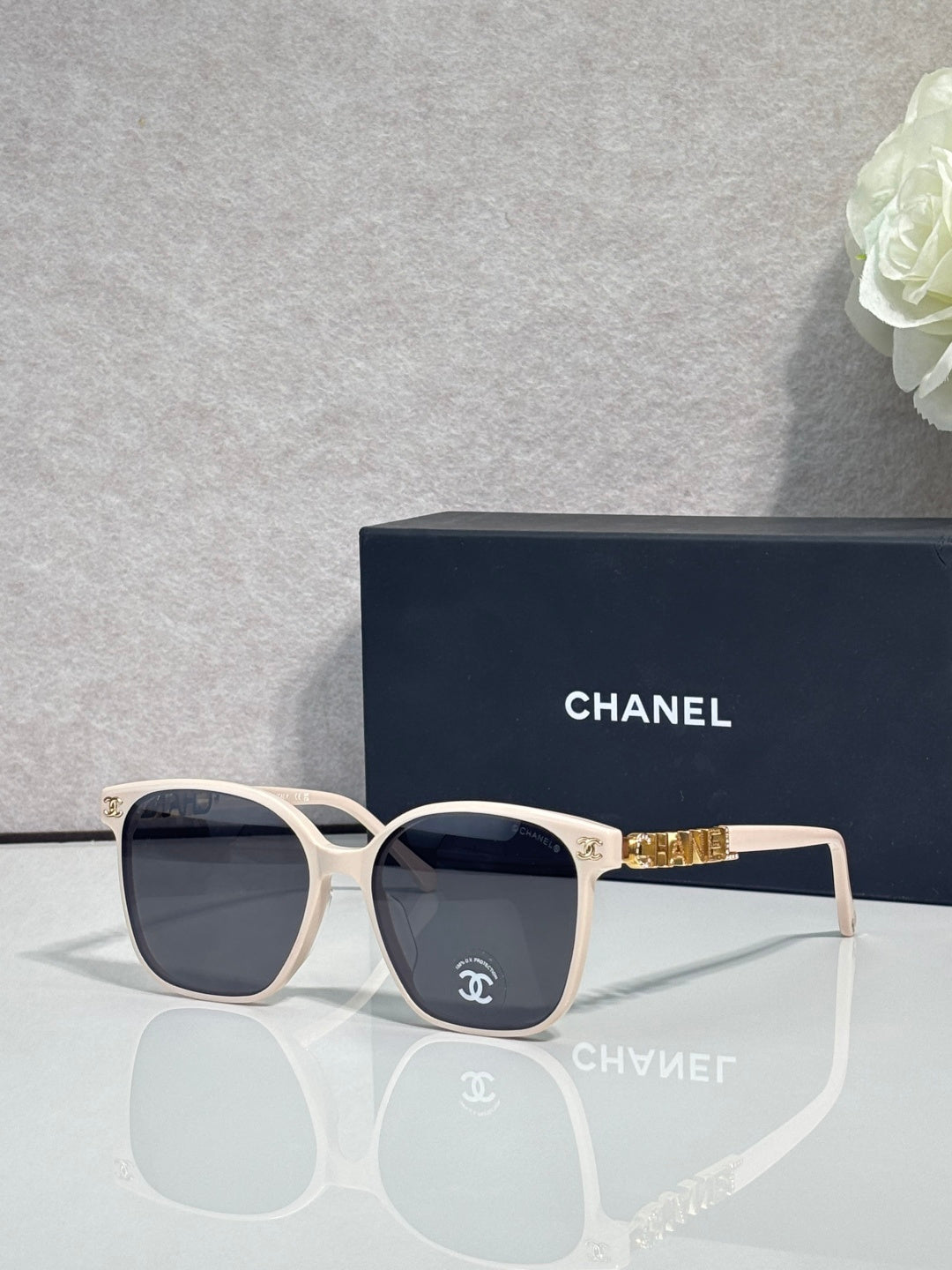 Chanel sunglasses with white frames and dark lenses, gold logo detail on temples