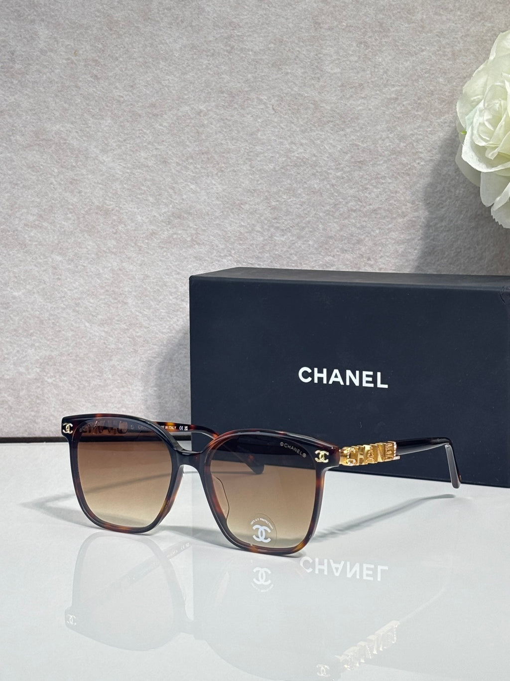 Chanel sunglasses with dark tortoise frames and tinted lenses, gold logo detail at temples