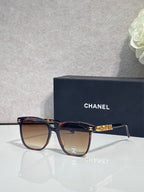 Chanel sunglasses with dark tortoise frames and tinted lenses, gold logo detail at temples