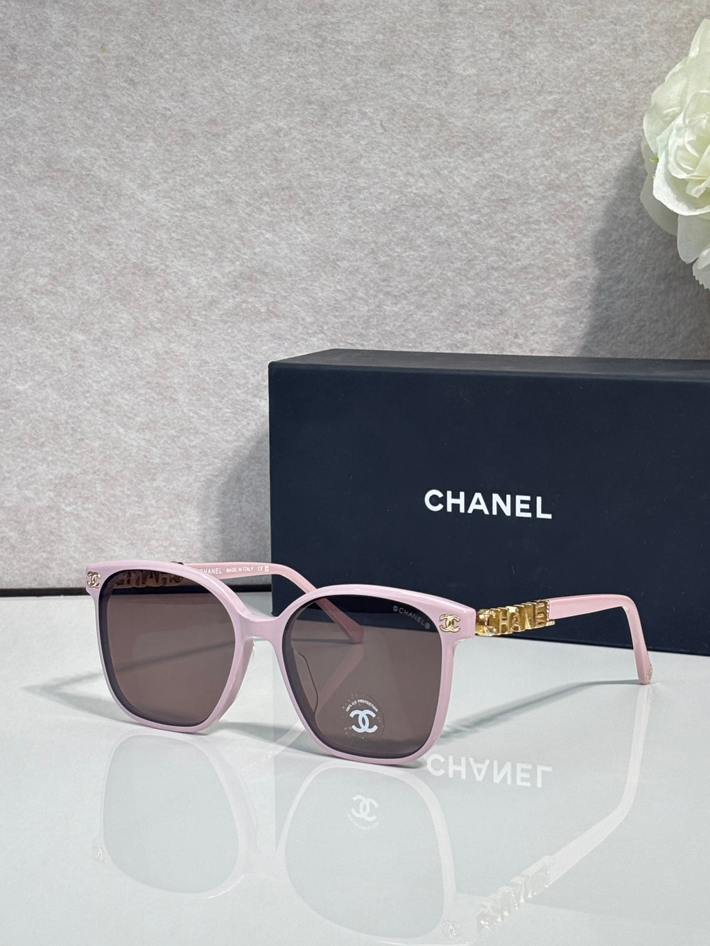 Chanel sunglasses with pink frames and brown tinted lenses, gold logo detail at temples