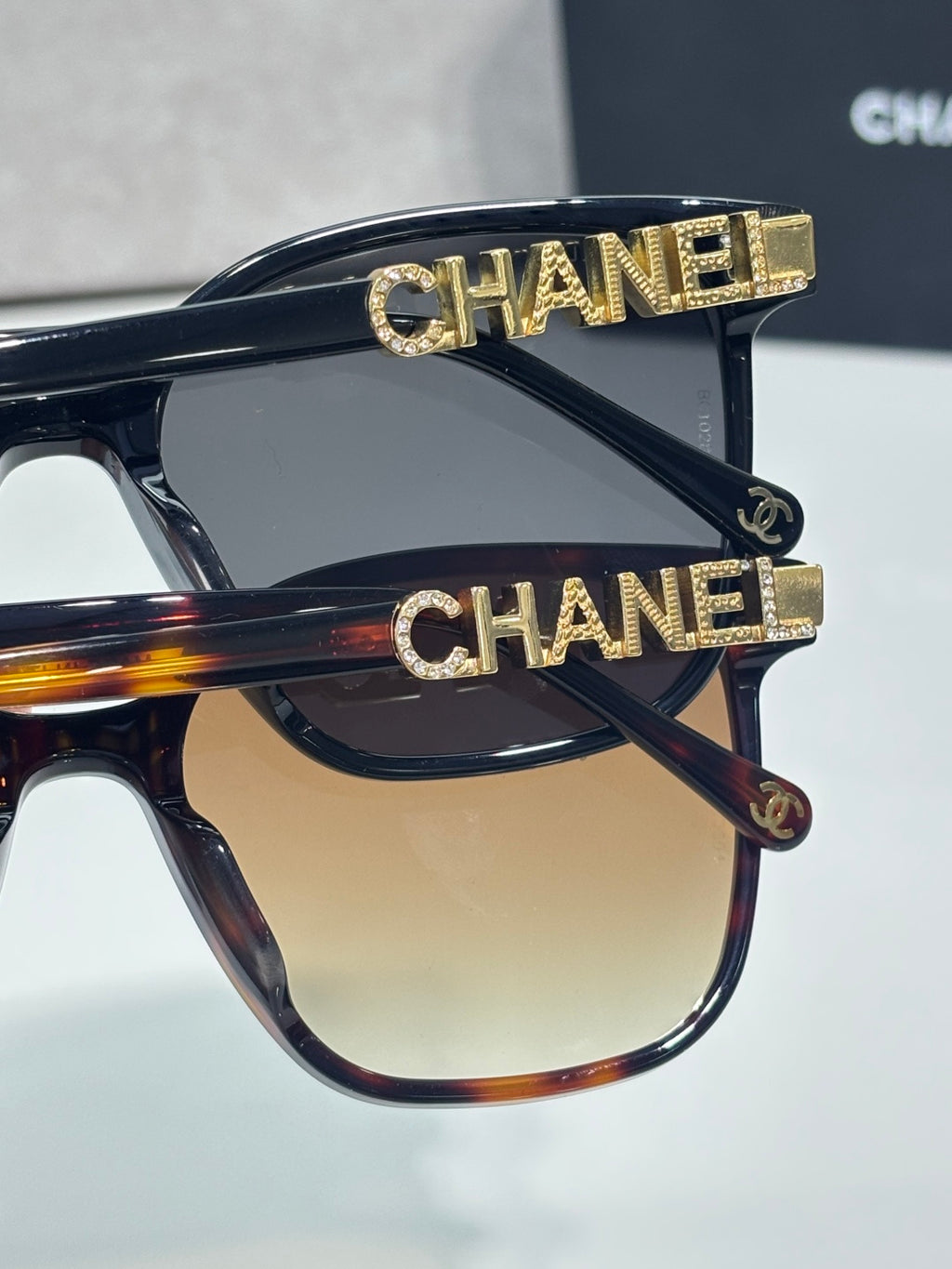 Chanel sunglasses with dark frames, gold CHANEL bar logo accents on top rim and temple