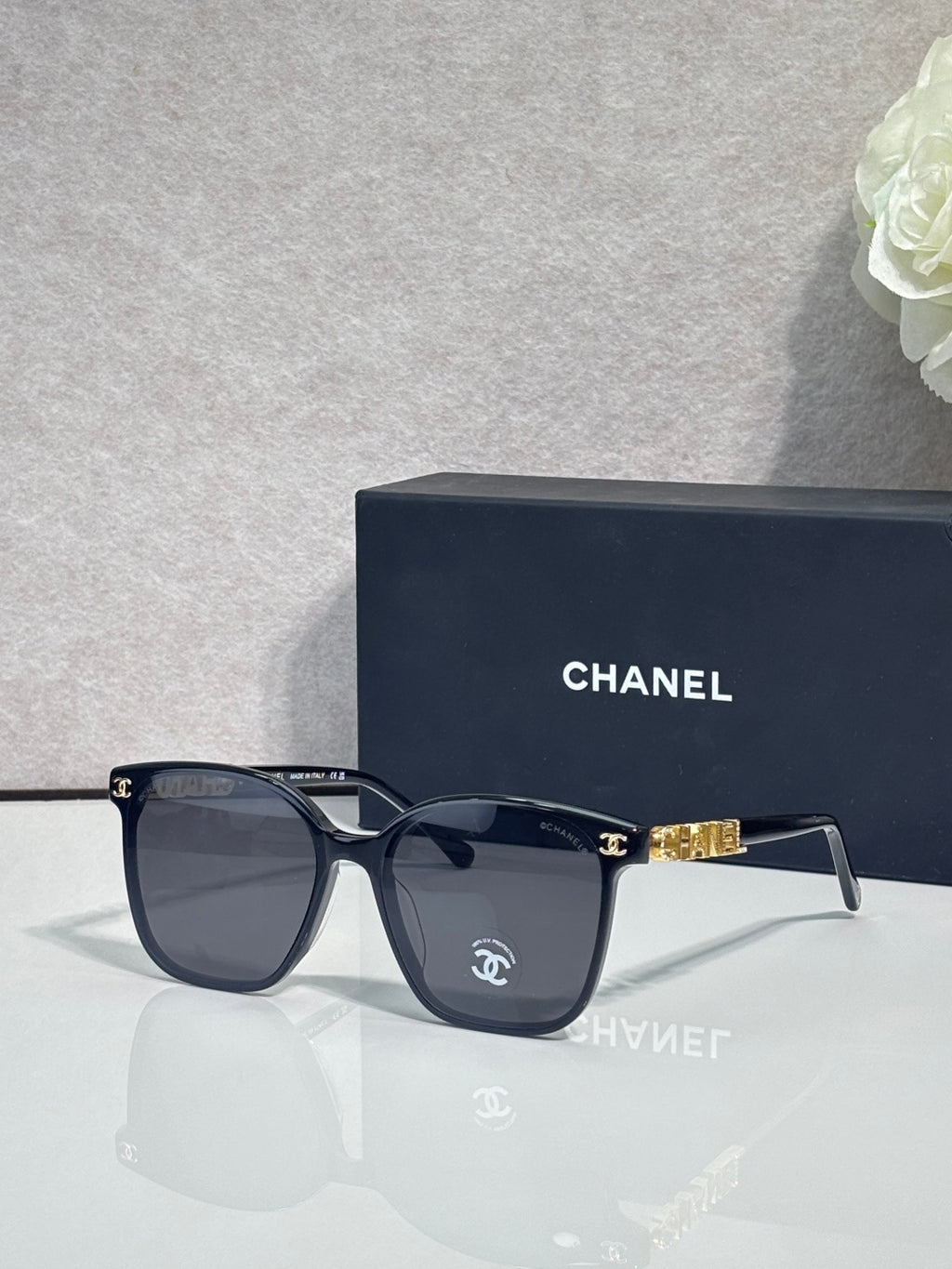 Chanel sunglasses with navy frames and dark tinted lenses, gold logo detail on temples