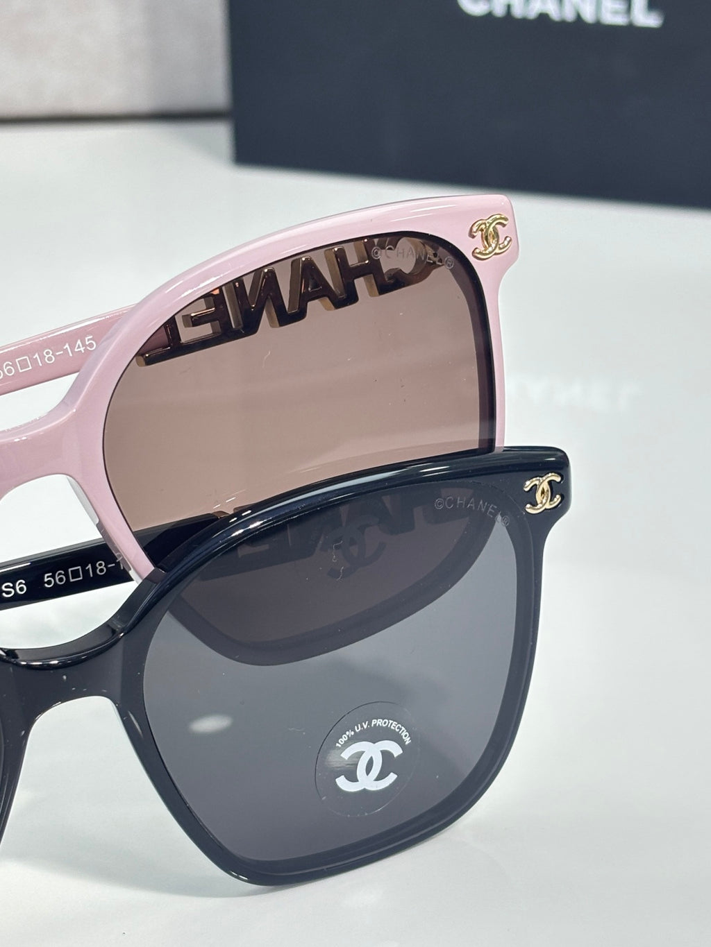 Chanel sunglasses close-up with pink frame and brown gradient lenses, gold logo hinge detail