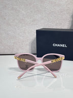 Chanel sunglasses with pink frames and brown tinted lenses, gold CHANEL logo detail on temples