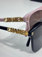 Chanel sunglasses close-up with pink frame and gold CHANEL bar logo accents on temple
