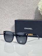 Square sunglasses with dark navy frames and dark gray lenses, gold logo on temple