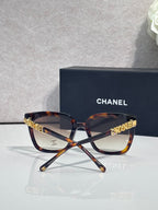 Square sunglasses with tortoiseshell frames and dark lenses, gold “CHANEL” logo on temples