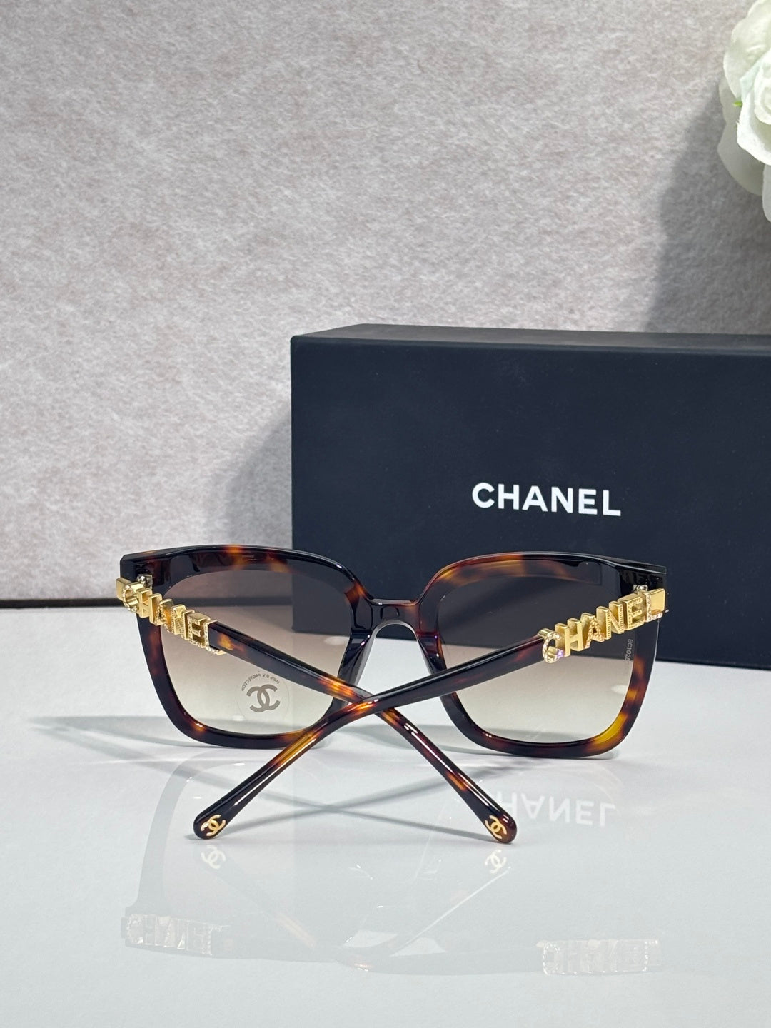 Square sunglasses with tortoiseshell frames and dark lenses, gold “CHANEL” logo on temples