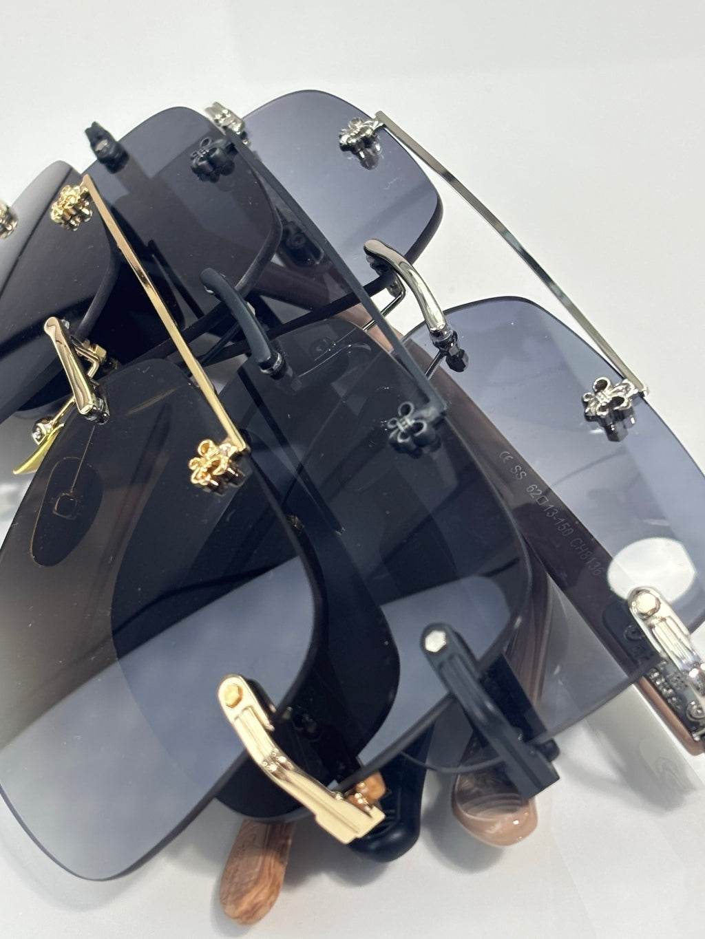 Angle view of chrome sunglasses with dark blue lenses, black frame, and gold-tone decorations.