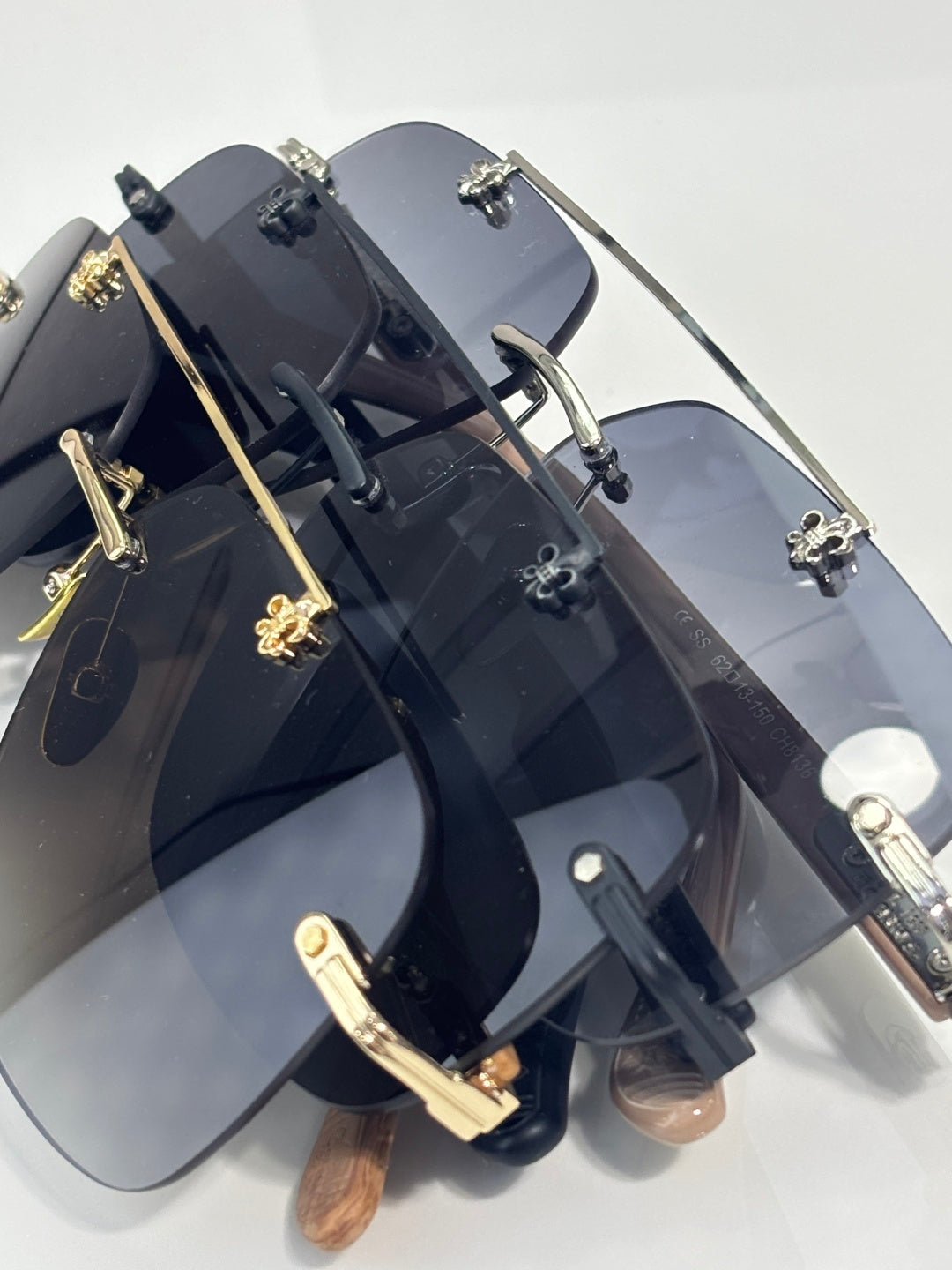 Angle view of chrome sunglasses with dark blue lenses, black frame, and gold-tone decorations.