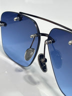 Close-up of chrome sunglasses showing dark blue lenses and black frame with gold-tone detail.